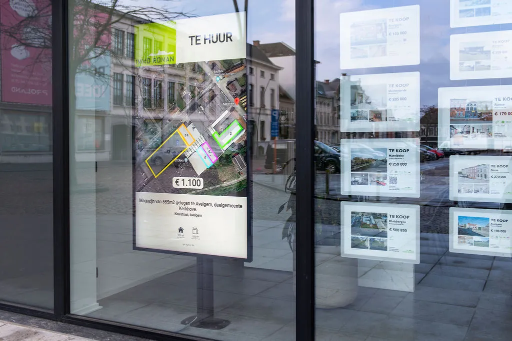 Vitrine d'Immo Roman avec un écran en portrait qui affiche un bien à louer