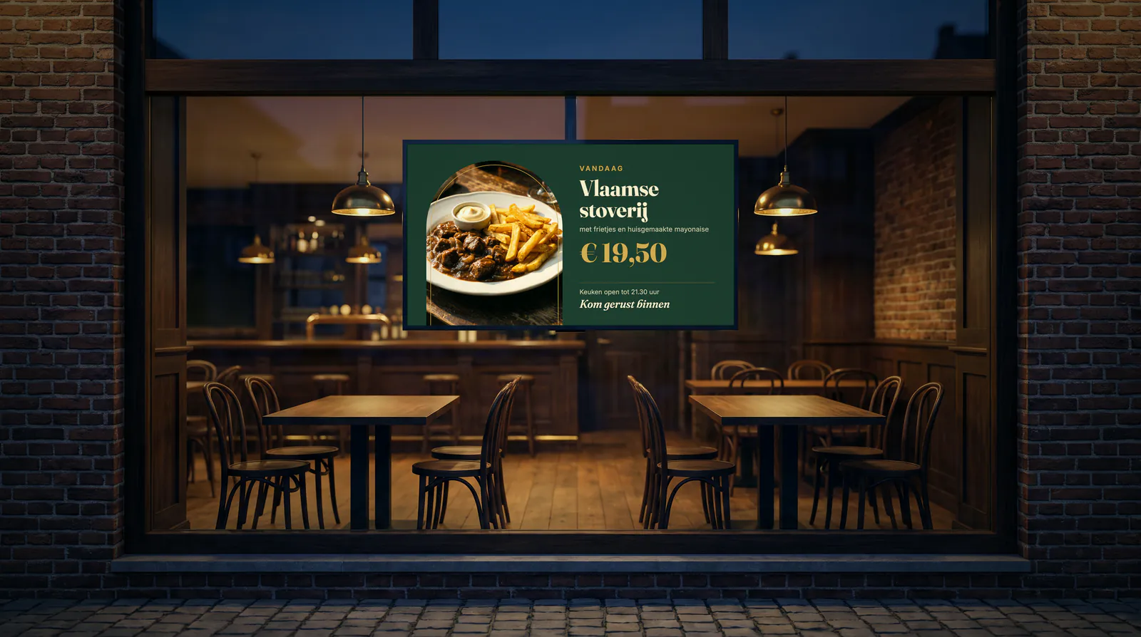 Fenêtre d'une brasserie à la tombée du jour, avec un écran qui affiche le plat du jour et le prix au-dessus de deux tables en bois